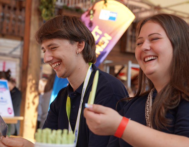 zwei lachende Azubis bei einer Messe