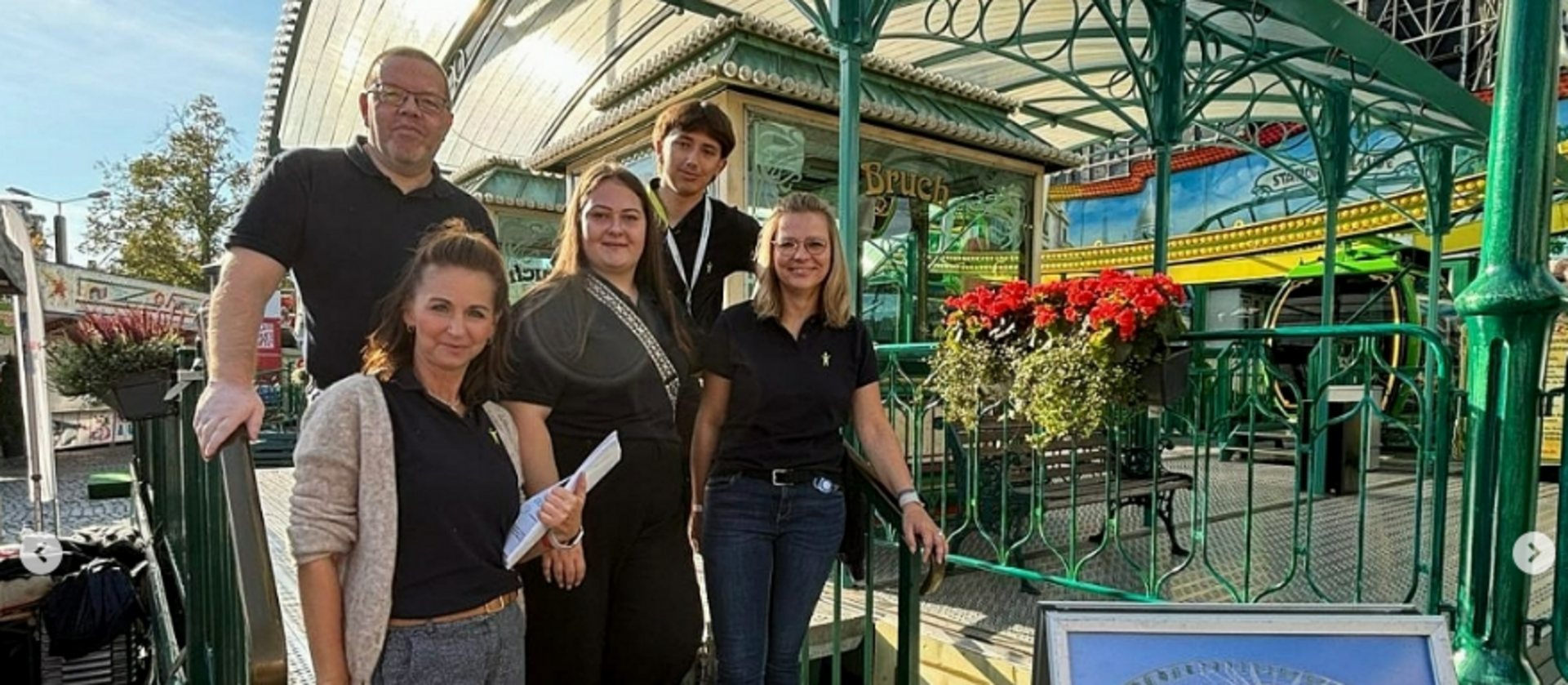 drei Frauen und zwei Männer stehen auf einer Stahltreppe im freien