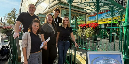 drei Frauen und zwei Männer stehen auf einer Stahltreppe im freien
