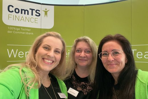 drei Frauen die freundlich in die Kamera lächeln vor der Messewand