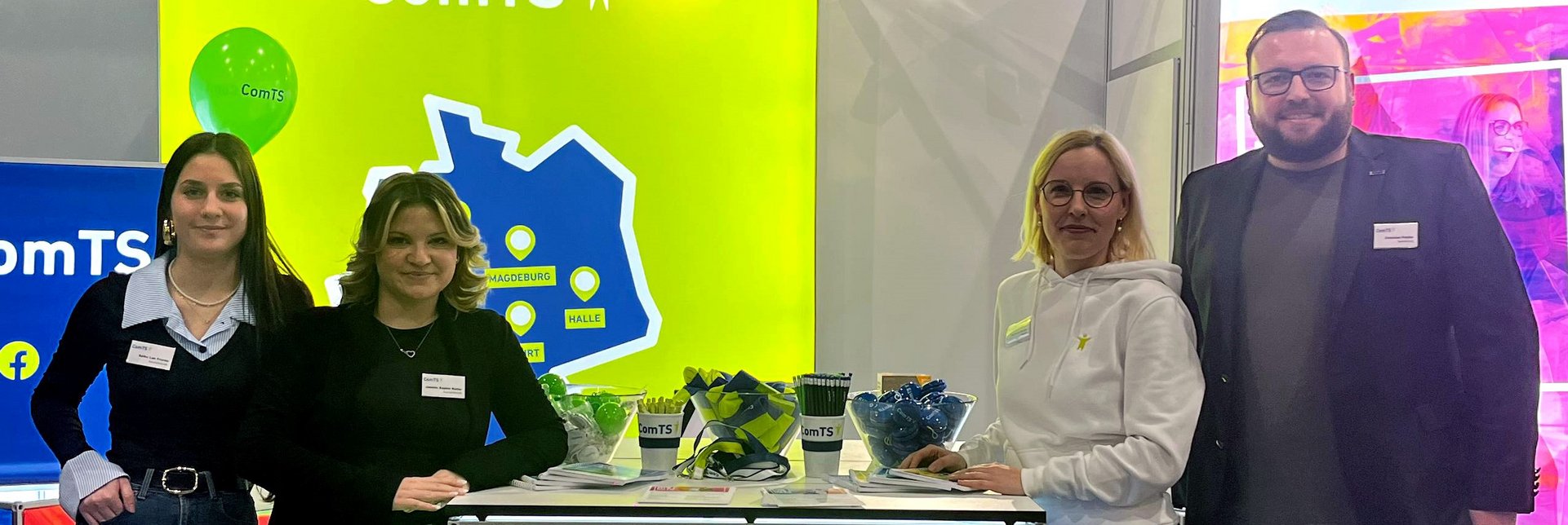 zwei Azubis links vom Messewürfel und eine Frau und ein Mann rechts vom Messewürfel