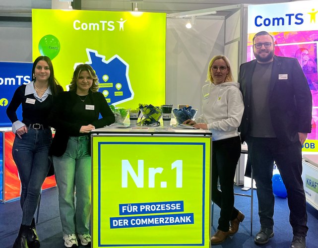 zwei Azubis links vom Messewürfel und eine Frau und ein Mann rechts vom Messewürfel